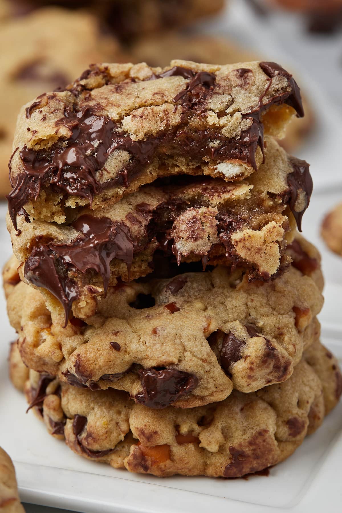 Close up of salty pretzel chocolate chip cookies stacked on a square white plate.