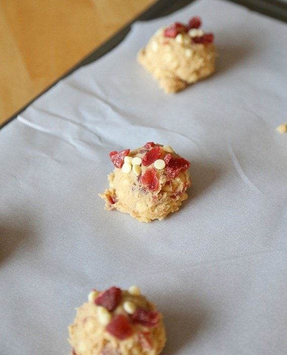 Unbaked strawberry cookie dough balls on a sheet of parchment paper.