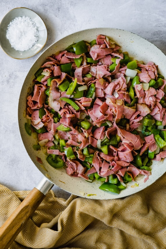 Roast beef, peppers, and onions in a pan.