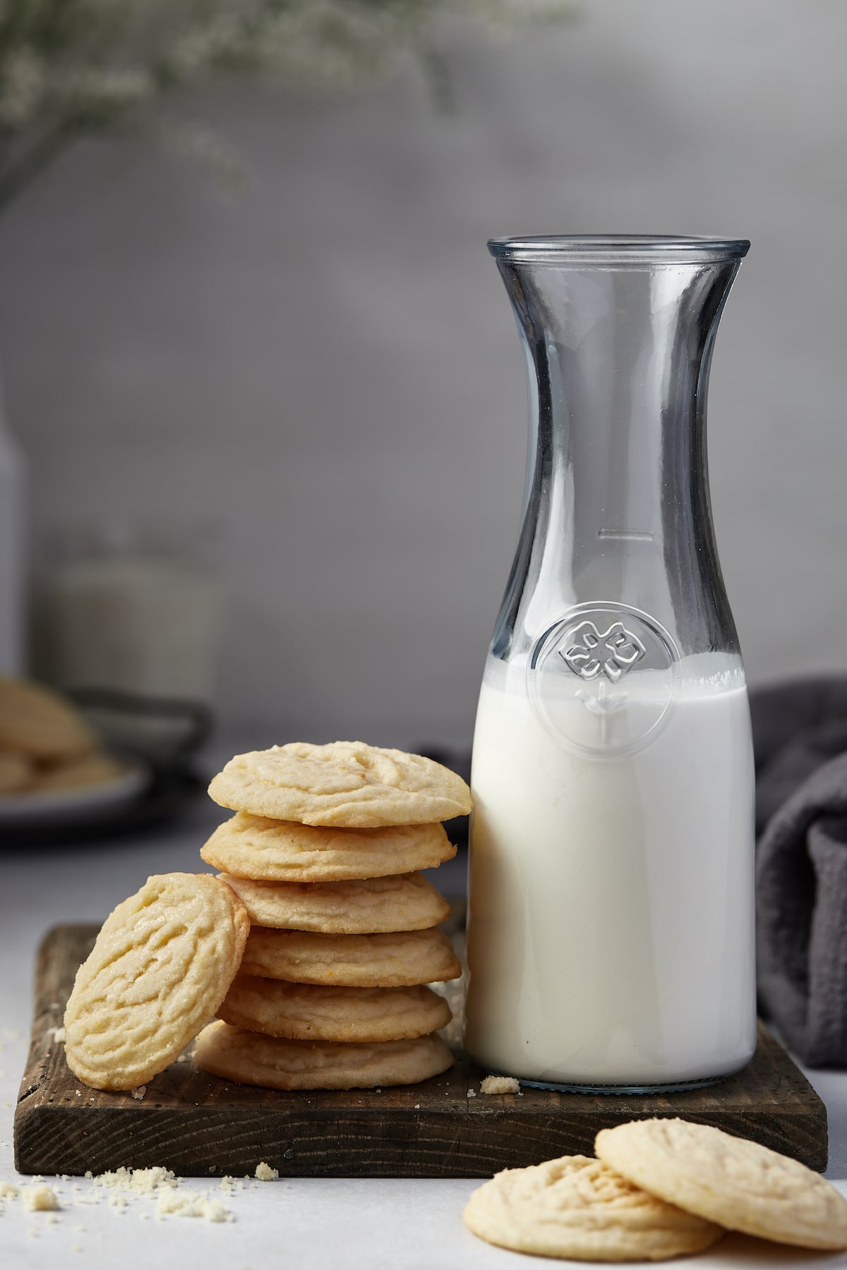 A stack of sugar cookies next to a jug of milk.