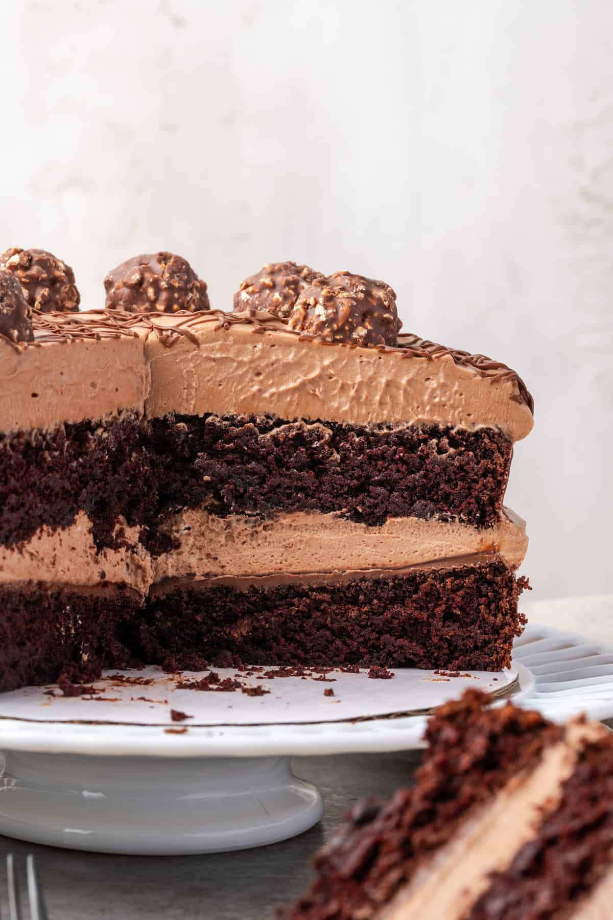 Side view of chocolate hazelnut cake with a large slice missing, revealing the layers of hazelnut mousse.
