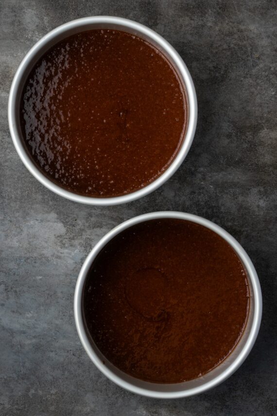 Two round cake pans filled with chocolate cake batter.