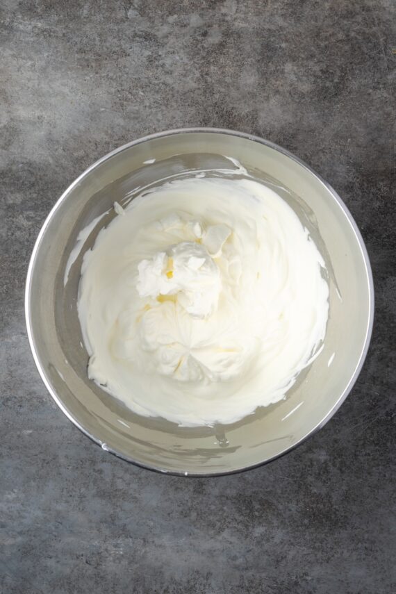 Whipped cream in a metal mixing bowl.