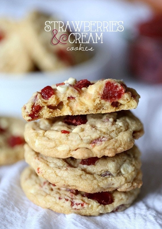 Title image for Strawberry White Chocolate Chip Cookies featuring a stack of strawberry cookies on a white cloth.
