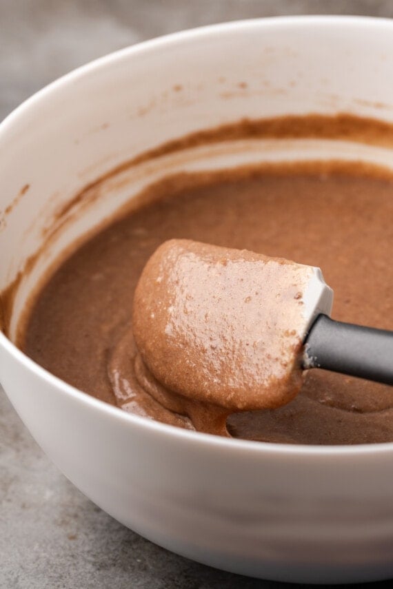 Chocolate sheet cake batter in a mixing bowl with a rubber spatula.