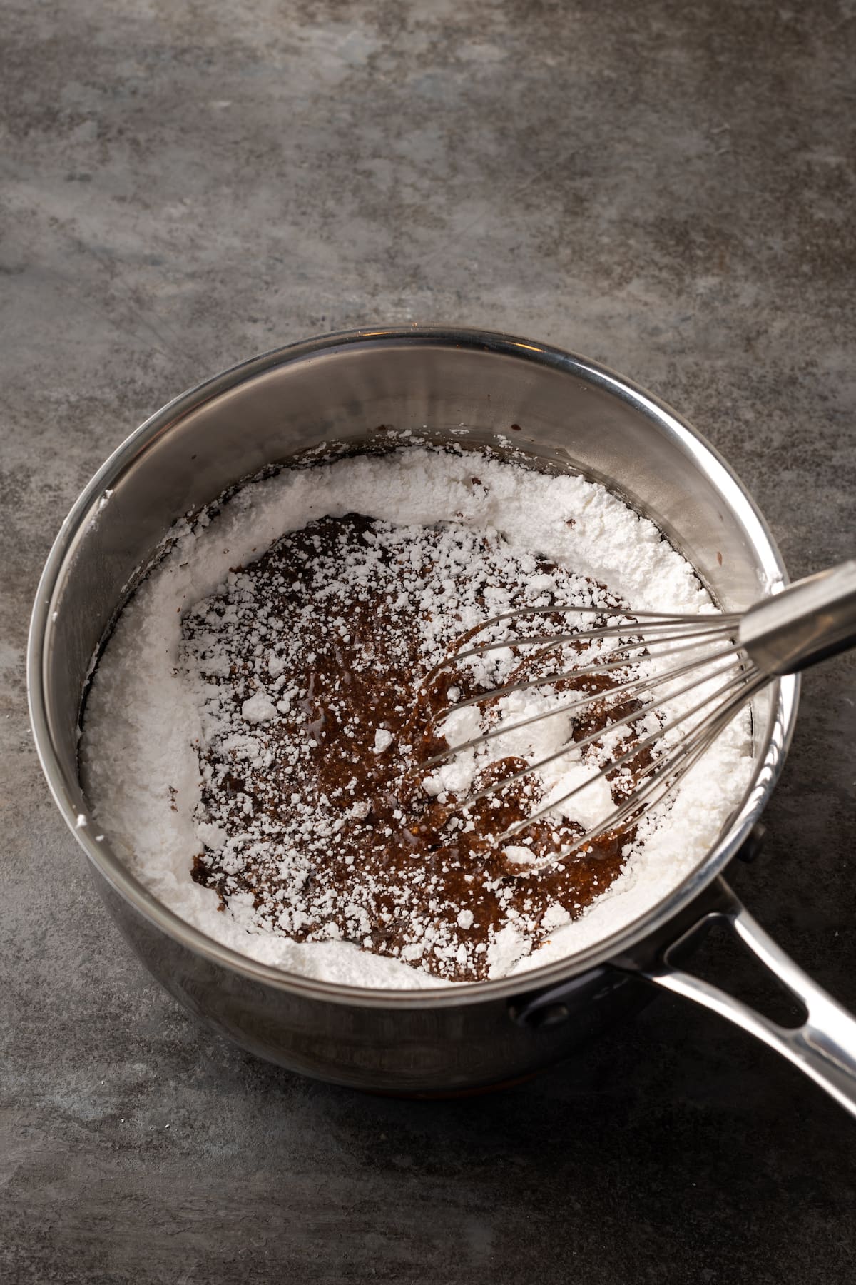 Powdered sugar and vanilla is whisked into the cocoa mixture in a saucepan.