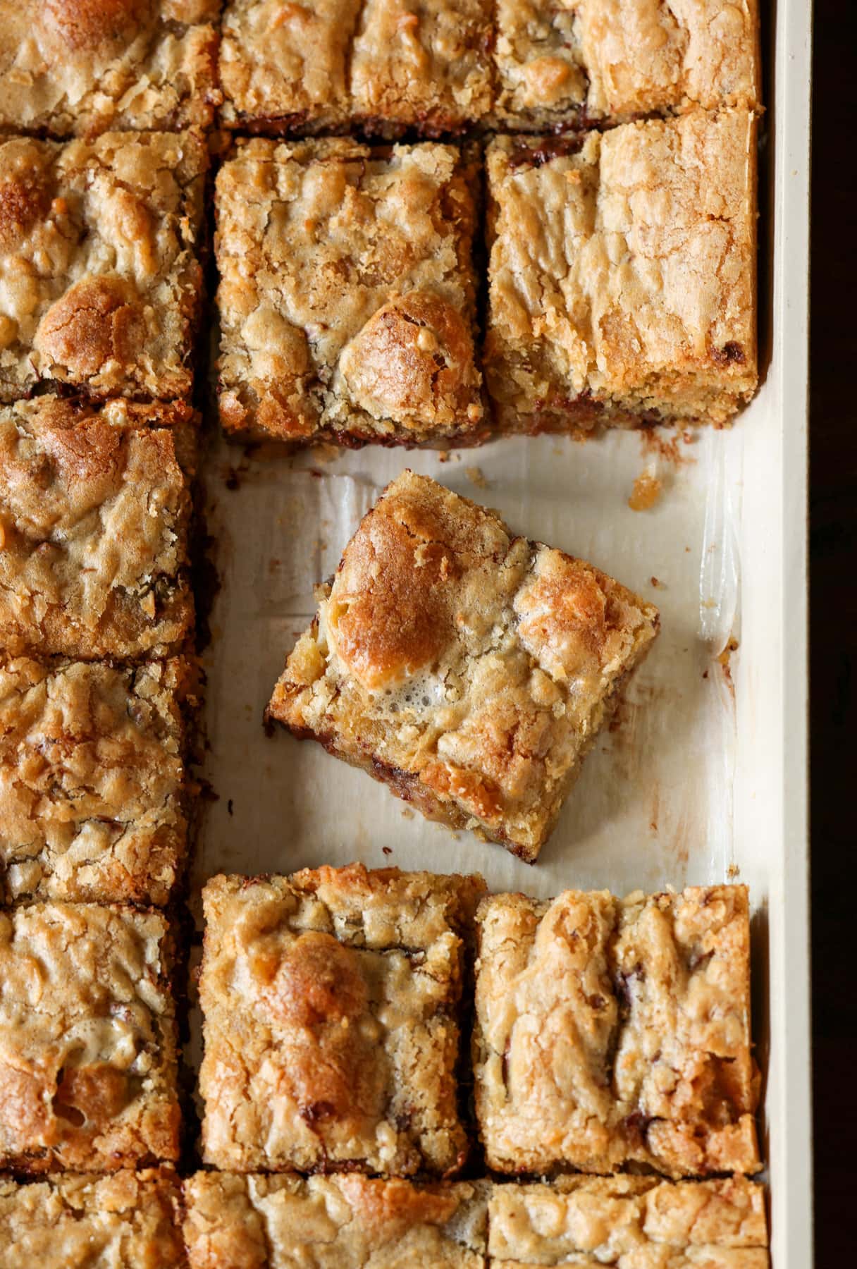 Cut blondies in a baking pan lined with parchment paper