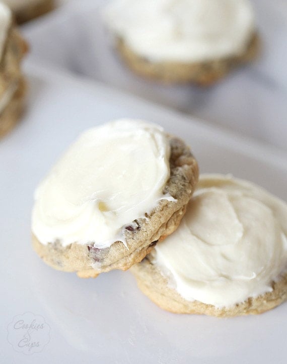 Ooey-gooey chocolate chip marshmallow cookies are thick, soft-baked cookies topped with marshmallows and sweet cream cheese frosting. Two frosted chocolate chip marshmallow cookies.