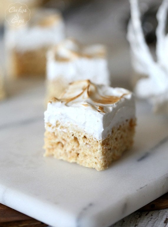 Close-up of a lemon meringue rice krispie treat on a marble surface, with more krispie treats in the background.
