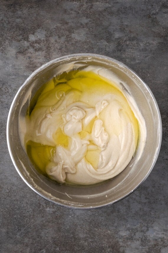 Egg whites added to cake batter in a metal mixing bowl.