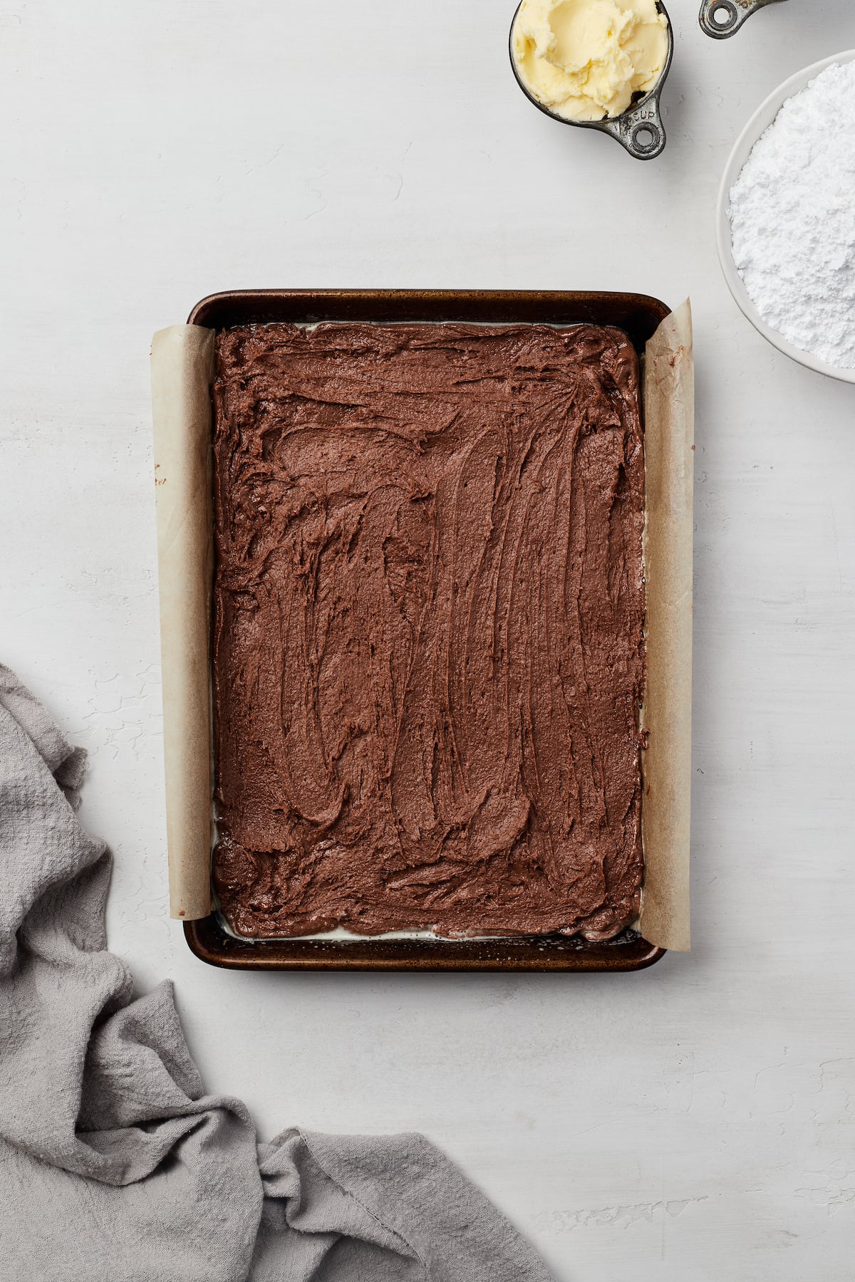 Chocolate brownie batter spread into a jelly roll pan.