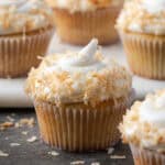 Almond cupcakes with swirls of coconut buttercream topped with toasted coconut.