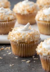 Almond cupcakes with swirls of coconut buttercream topped with toasted coconut.