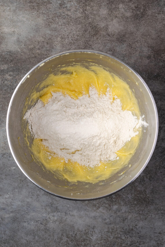 Flour added to the wet ingredients in a mixing bowl.