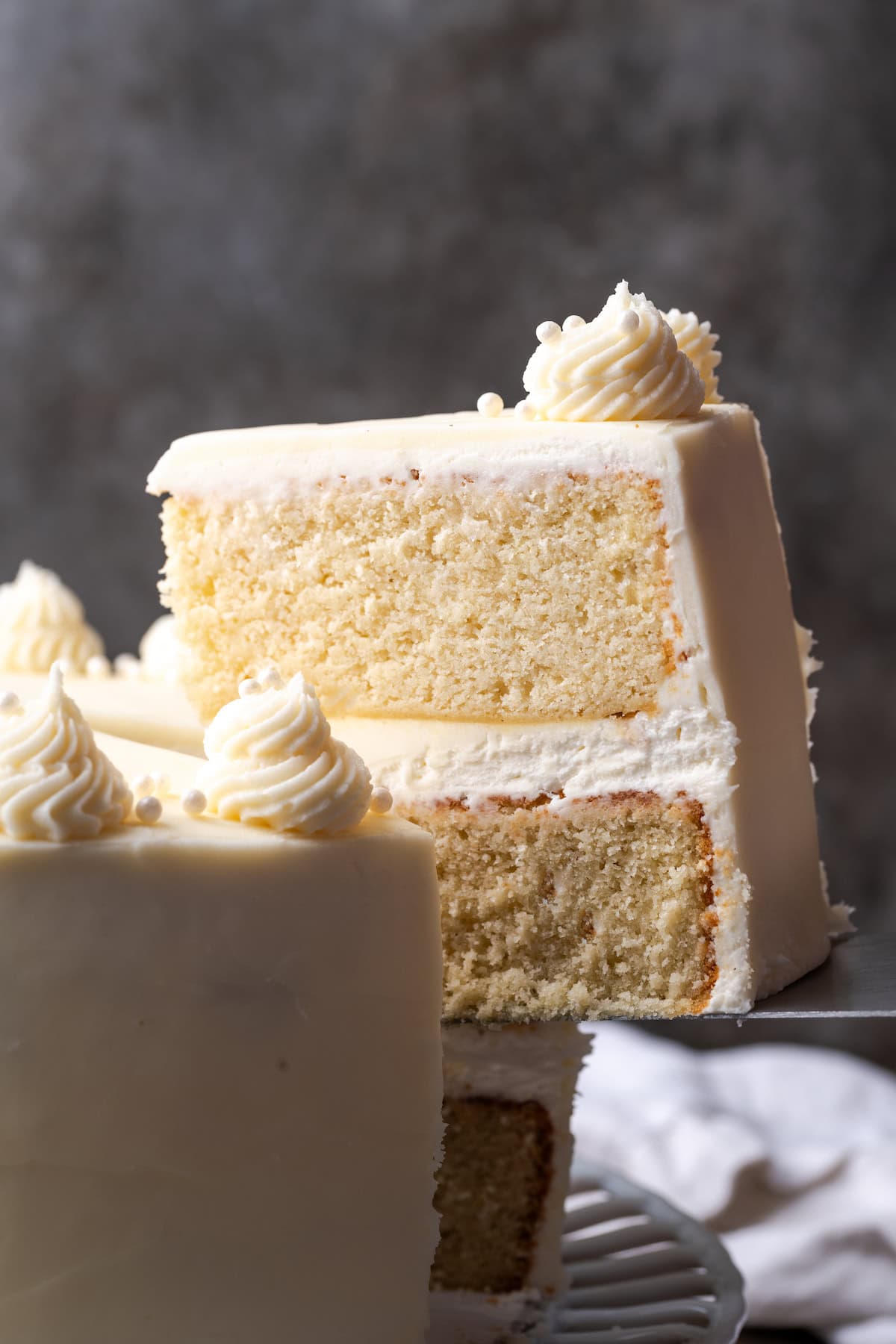 Side view of a slice being lifted from a vanilla layer cake.