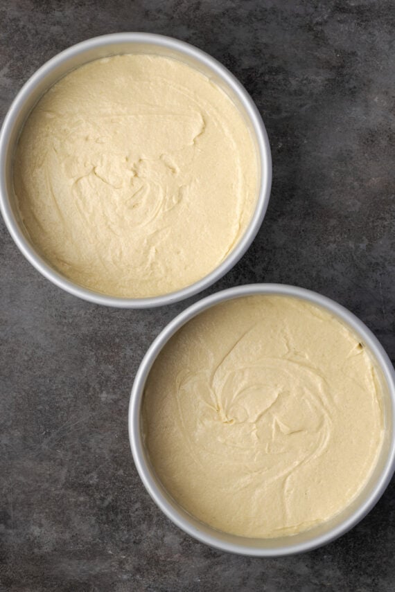 Two round cake pans filled with vanilla cake batter.