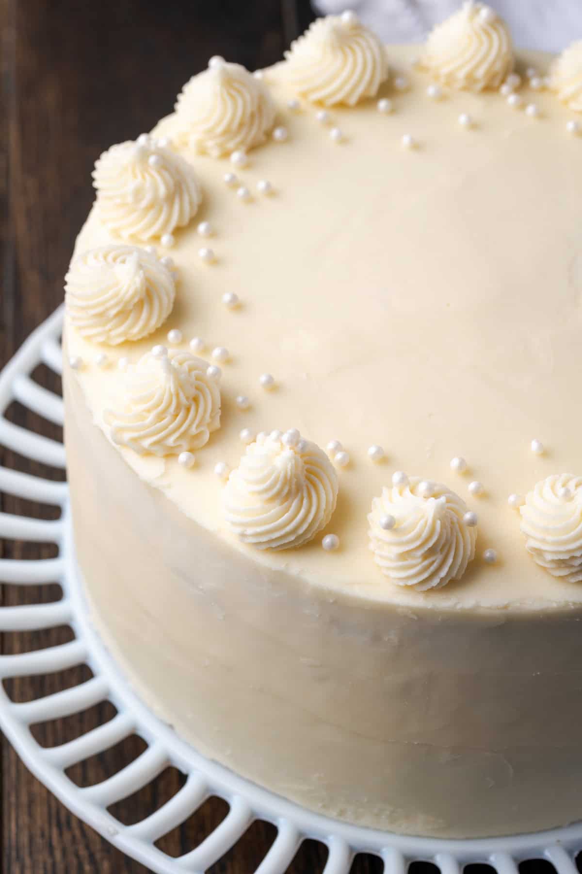 Overhead view of a frosted vanilla layer cake on a cake stand.