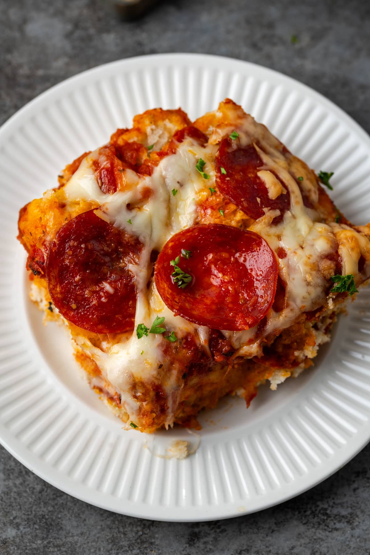 Overhead view of a serving of pizza casserole on a white plate.