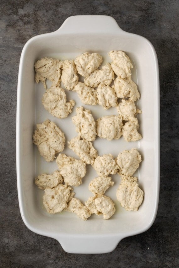 Pieces of Bisquick dough arranged in the bottom of a baking dish.