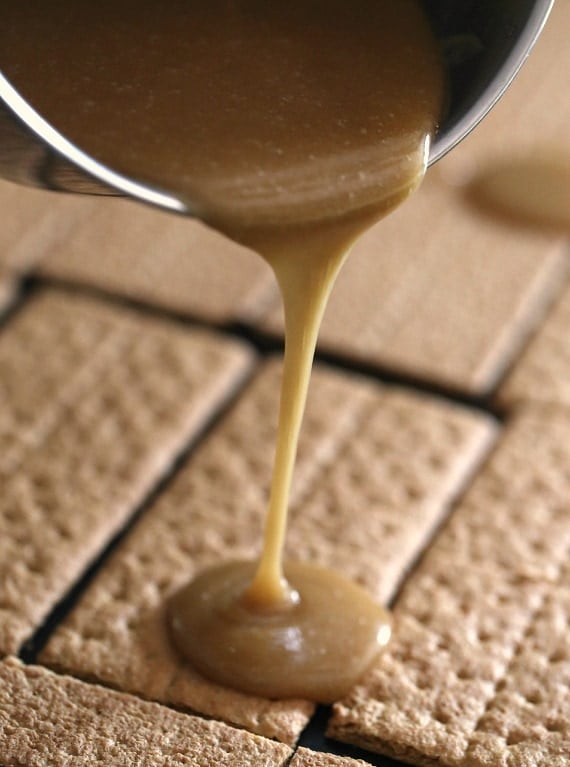 Pouring the butterscotch/caramel sauce over top graham crackers for praline crack!