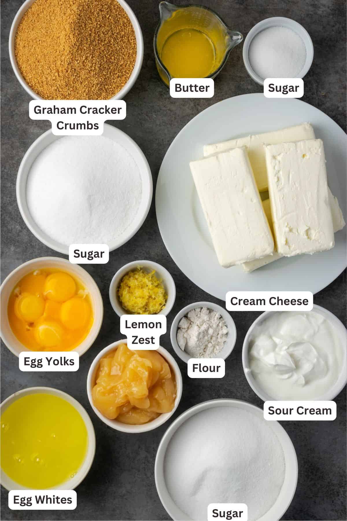 This zesty lemon meringue cheesecake has a smooth and creamy lemon filling, buttery graham cracker crust, and pillows of homemade meringue! Lemon meringue cheesecake ingredients with text labels overlaying each ingredient.