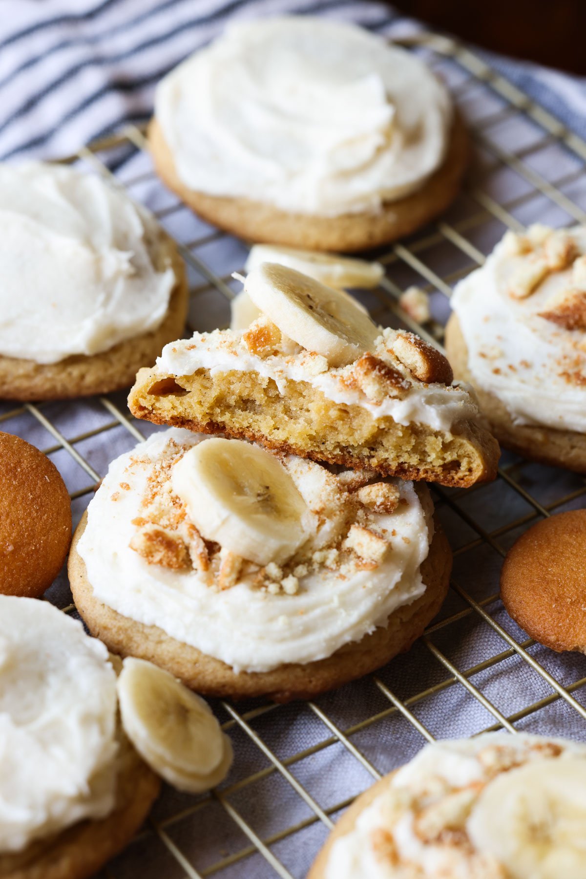 Half a banana pudding cookie stacked on a wire rack with frosting and crushed cookies