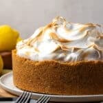 Side view of lemon meringue cheesecake with a toasted top on a plate.