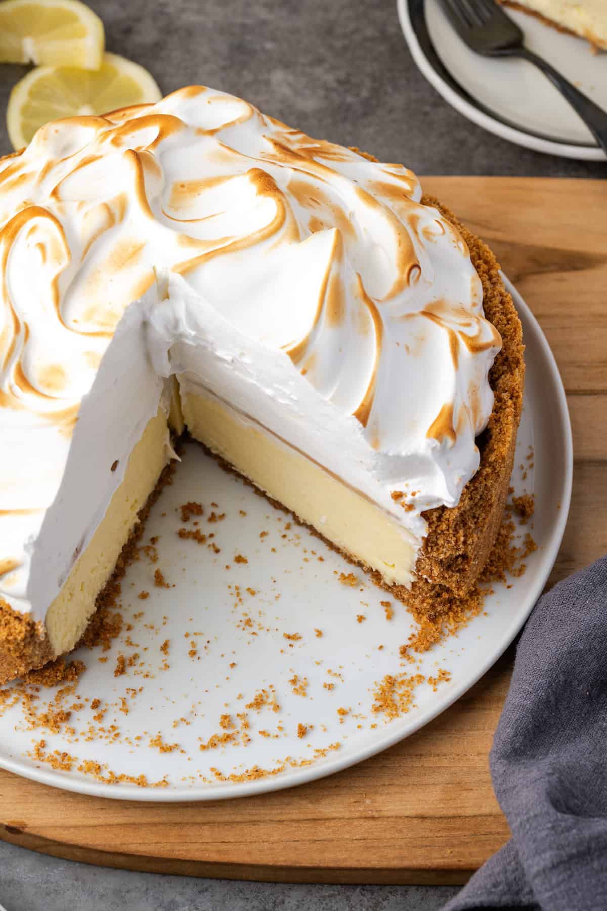 This zesty lemon meringue cheesecake has a smooth and creamy lemon filling, buttery graham cracker crust, and pillows of homemade meringue! Overhead view of lemon meringue cheesecake with a large slice missing.