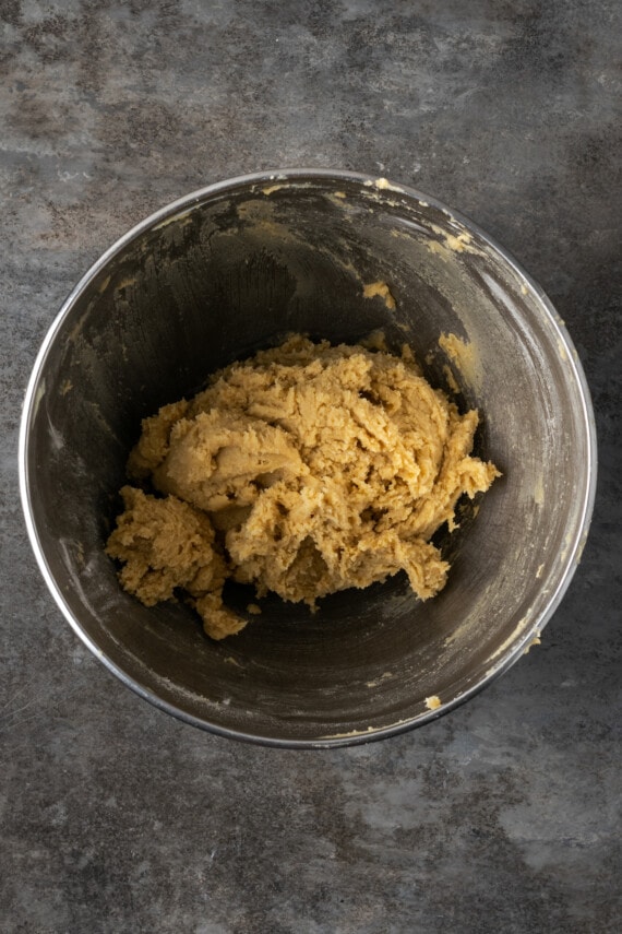 Cookie dough for praline cookies in a metal mixing bowl.