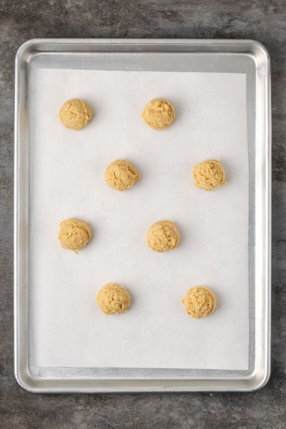 Cookie dough balls portioned onto a lined baking sheet.