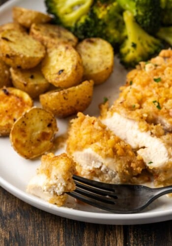 Sliced chicken on a plate with potatoes and broccoli.