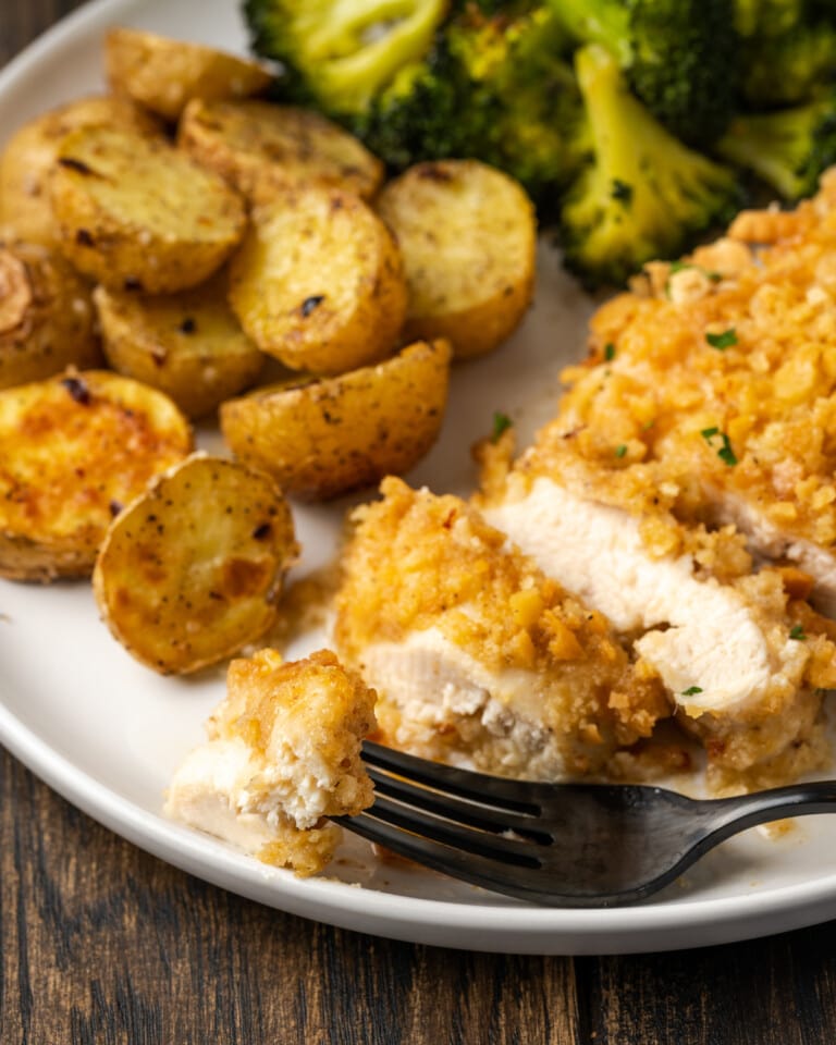 Sliced chicken on a plate with potatoes and broccoli.