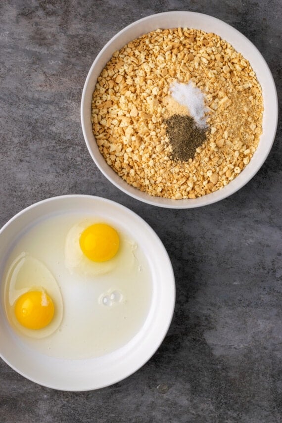 Two shallow bowls with cracked eggs and cracker crumbs and spices.