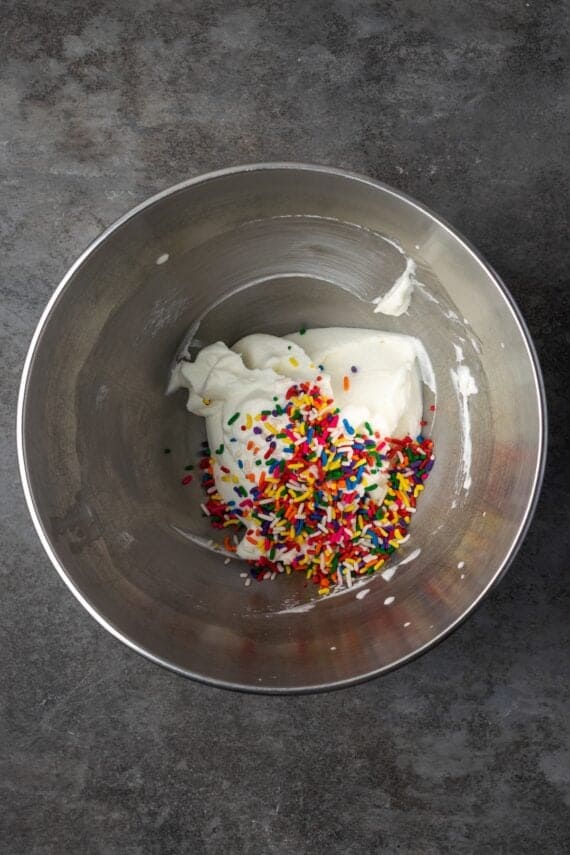 Sprinkles added to whipped cream in a bowl.