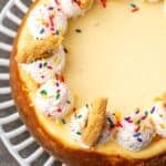 Overhead view of sugar cookie cheesecake topped with swirls of sprinkle whipped cream and broken cookies.