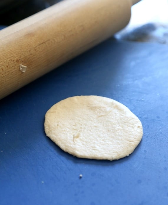 Close-up of a rolling pin with a circle of dough on a cutting board