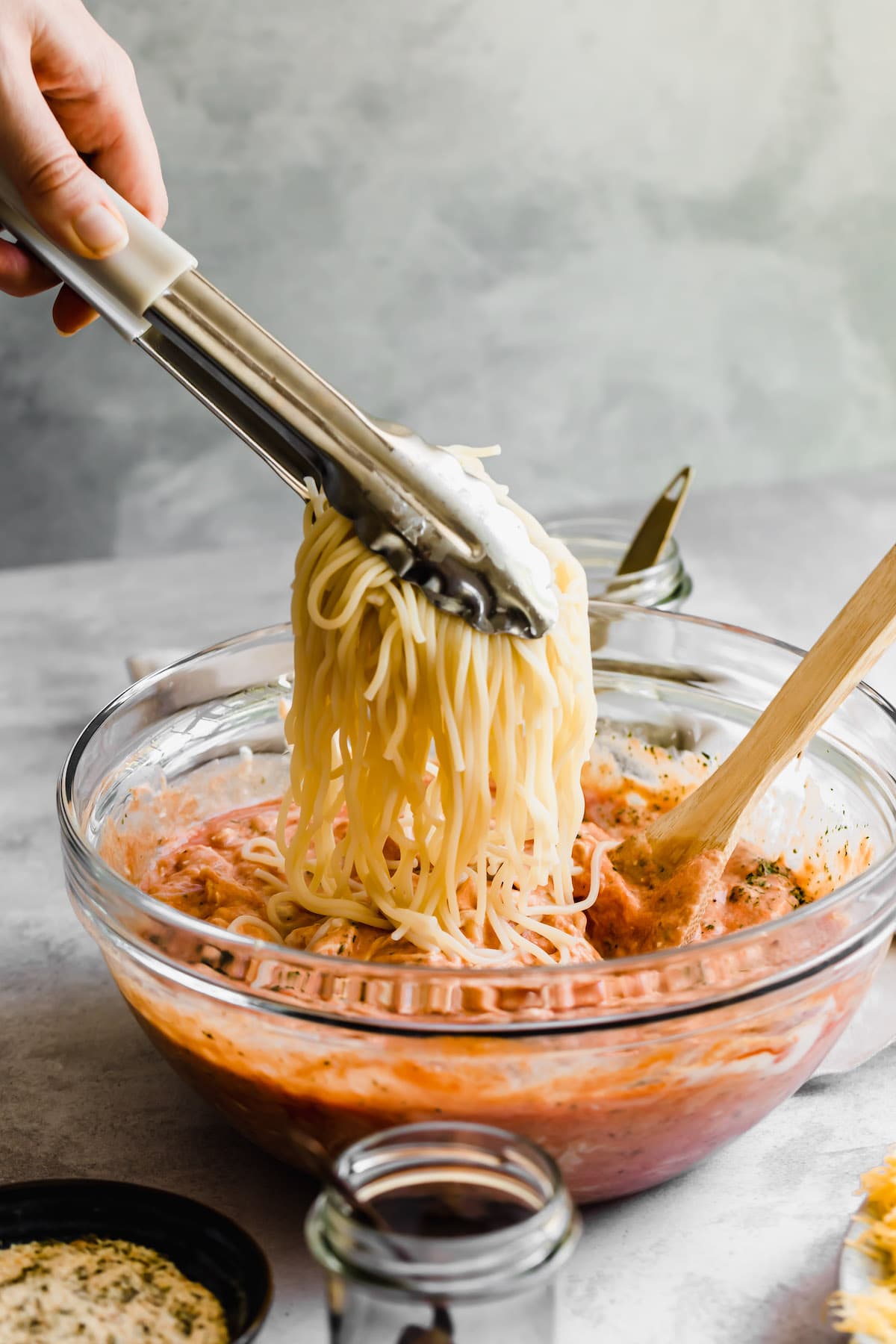 Cooked spaghetti above a bowl of sauce.