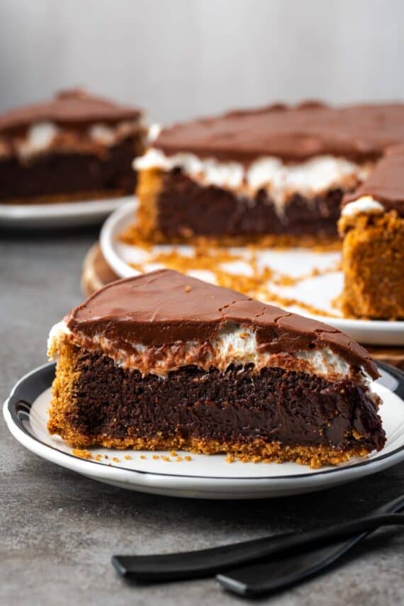 A slice of brownie pie on a plate with the rest of the pie in the background.