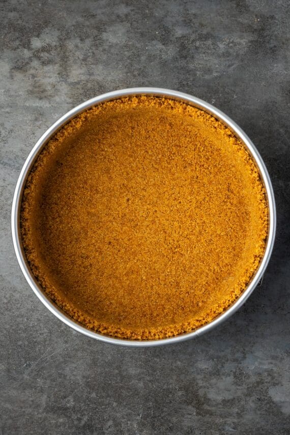 Graham cracker crust pressed inside a springform pan.