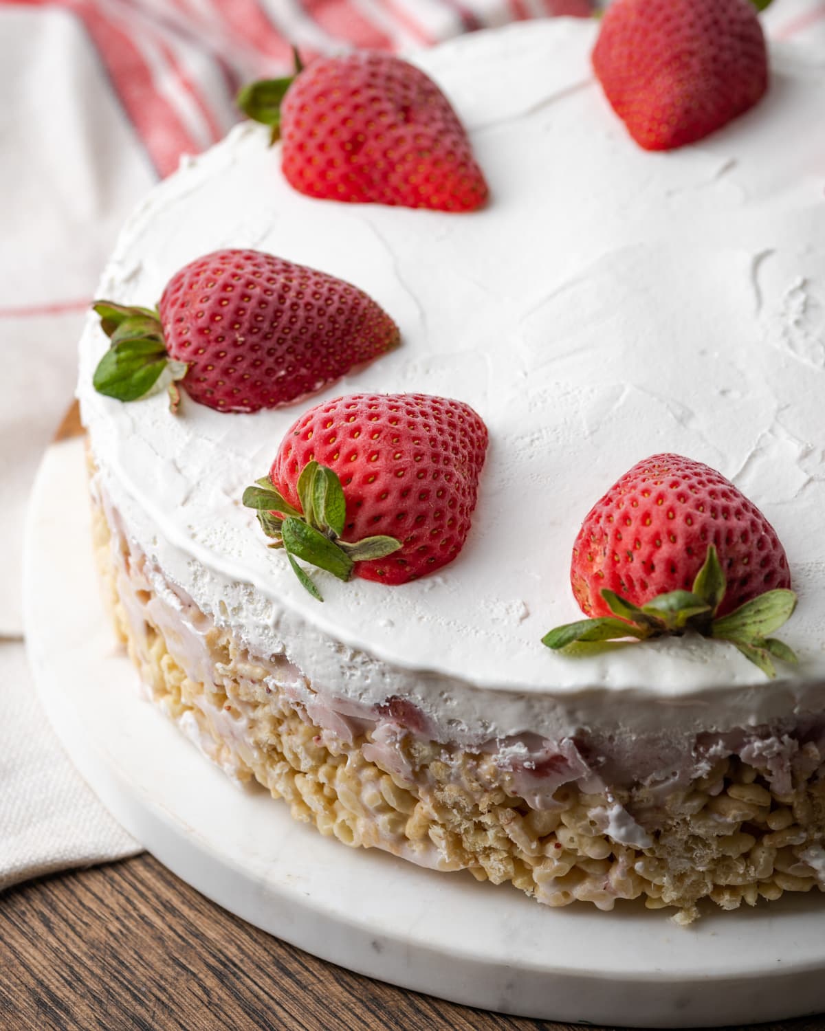 A whole Krispie Treat ice cream pie topped with whipped cream and fresh strawberries.