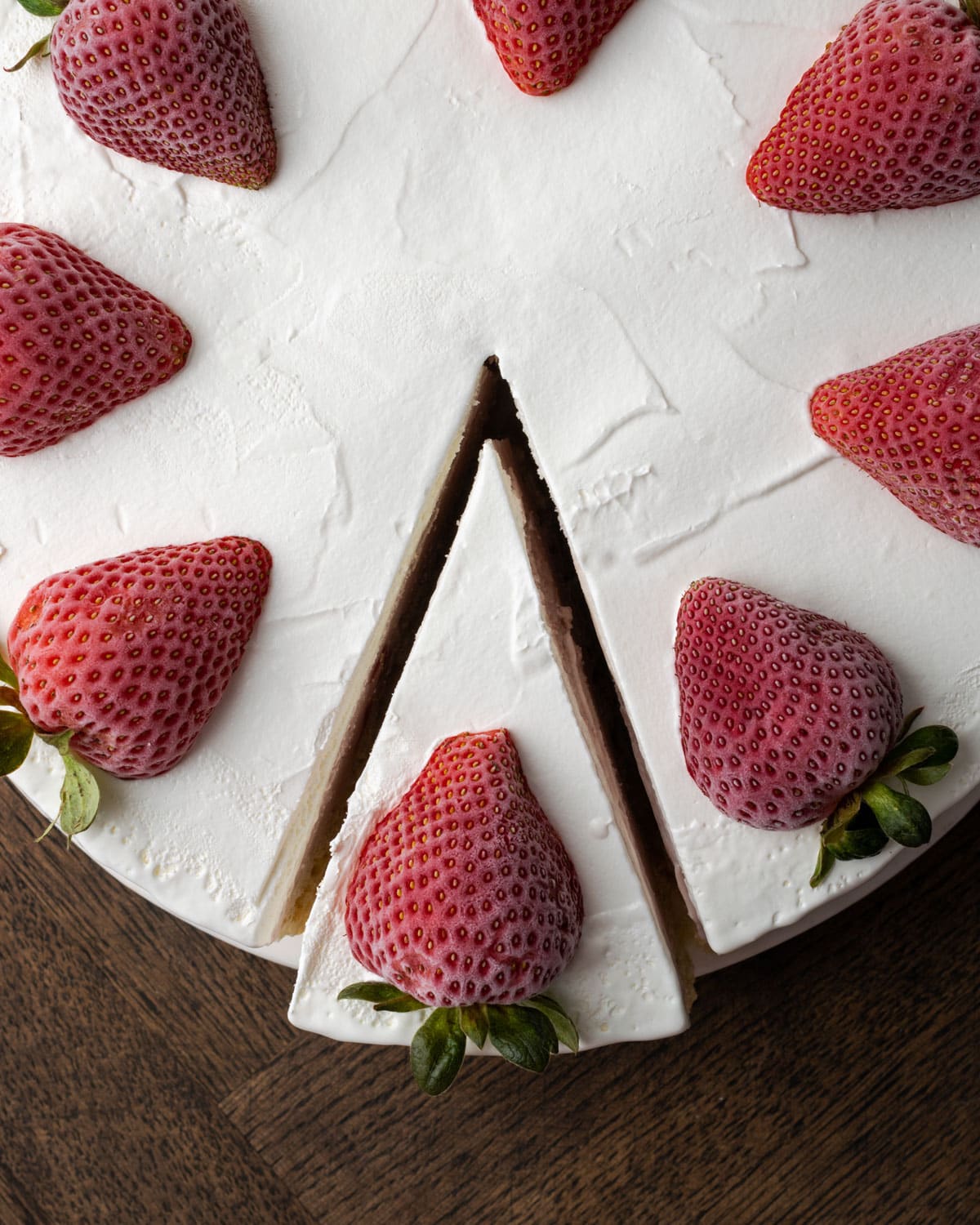 Top view of a Krispie Treat ice cream pie topped with whipped cream and fresh strawberries, with one slice cut away from the pie.