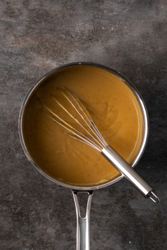 Overhead view of bourbon butterscotch pudding in a saucepan with a whisk.