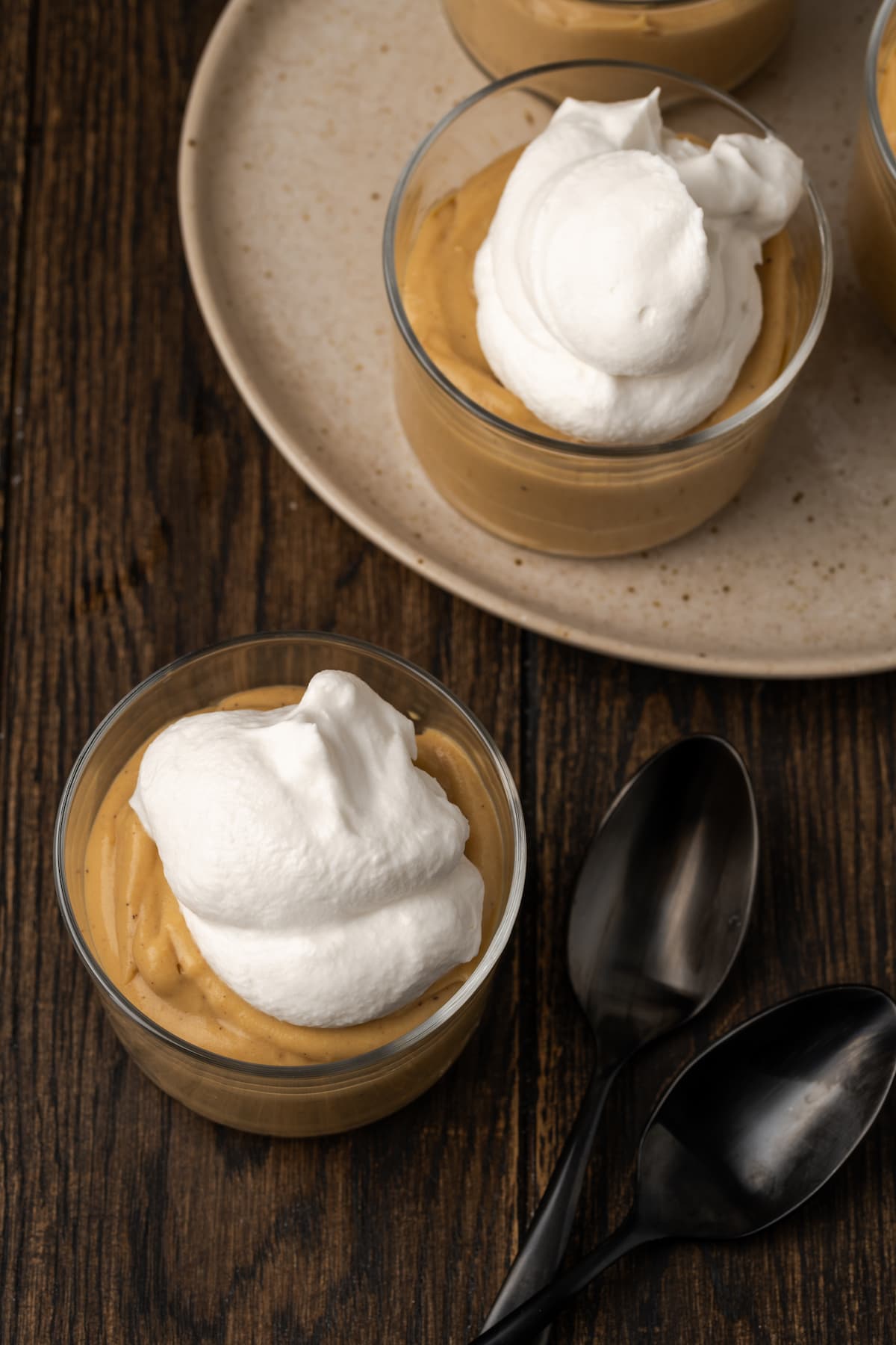 Overhead view of bourbon butterscotch pudding served in glasses topped with whipped cream.