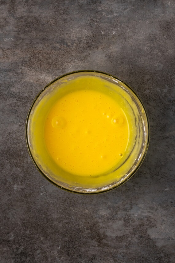 Whisked egg yolks in a glass bowl.