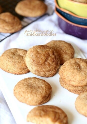 Assorted pumpkin snickerdoodles scattered on a white cutting board.