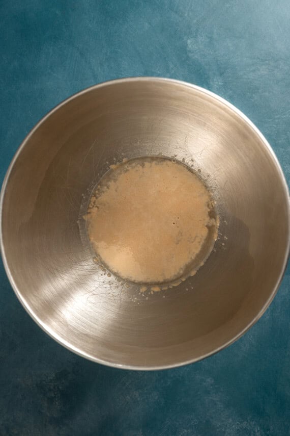 Activated yeast in warm water in a metal mixing bowl.