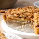 Side view of an apple crumble tart with a large slice missing.