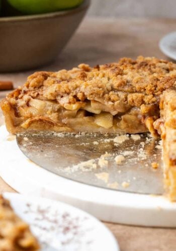 Side view of an apple crumble tart with a large slice missing.