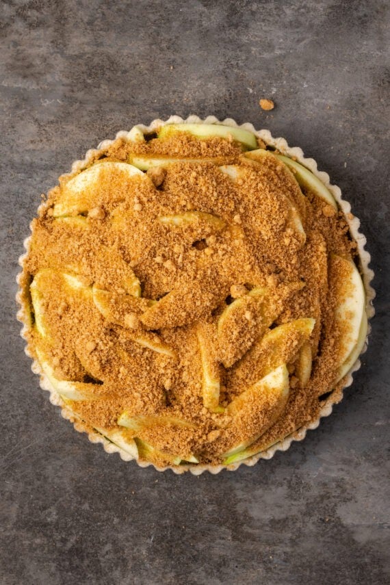 Cinnamon sugar added over top of the apple slices in a pie crust.