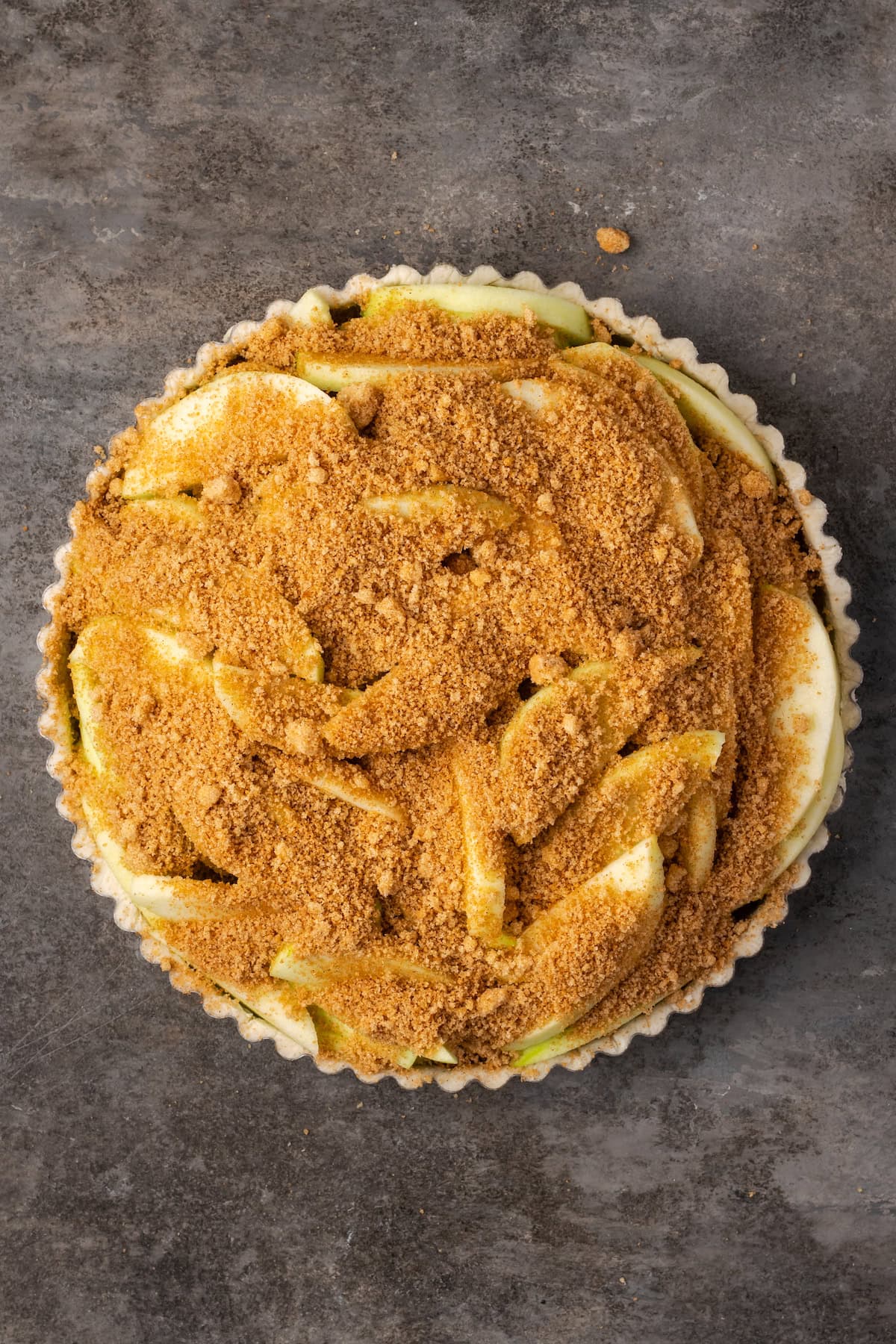 Cinnamon sugar added over top of the apple slices in a pie crust.